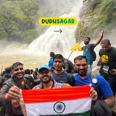 A few members of the crew holding the flag proudly in front of the mighty Dudhsagar falls.