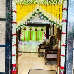 A beautiful floral 'thoran' or archway for a house entrance. Made with yellow and white flowers, it creates a welcoming and auspicious entryway, with a glimpse of the indoor decorations.