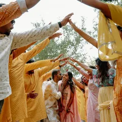 The groom is surrounded by his friends as they create an arch of hands for the couple to walk through during the Haldi ceremony. It's a beautiful symbol of their support and friendship.