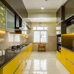 This parallel kitchen makes a bold statement with vibrant yellow glossy cabinets and a black granite countertop. The high-contrast design is both stylish and practical, with ample storage on both sides.