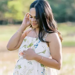 A serene solo portrait of the mother-to-be in a field at sunset. The soft light and her gentle expression create a feeling of peace and connection with nature.