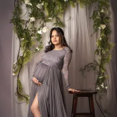 A full-length portrait showcasing a stunning grey lace and tulle gown. The floral vine backdrop adds a touch of natural elegance to this beautiful solo shot.