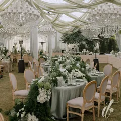 An example of our classic and timeless reception design, this 'Ivory Garden' theme features a stunning floral runner cascading down a long guest table. The space is illuminated by magnificent crystal chandeliers, blending natural elegance with sophisticated glamour.