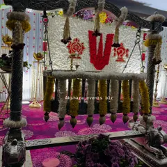 A beautifully decorated cradle for a naming ceremony. The setup features a backdrop of white flowers with a central 'Om' symbol, creating a serene and spiritual ambiance.