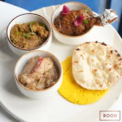 A platter from the 'Zaika e Rooh' pop-up, featuring a tasting of Chicken Qorma, Chicken Stew, and Mutton Hari Mirchein Keema, served with traditional sheermal and tandoori roti.