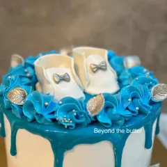 A close up of the adorable, handcrafted fondant baby booties that topped this "Welcome Baby" cake. The intricate details, like the tiny silver bows, make it extra special.
