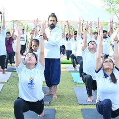 I provide an adjustment to a student in Anjaneyasana (Low Lunge) during our International Yoga Day celebration. Practicing together outdoors amplifies the sense of community.