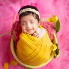That heart-melting newborn smile. I live for these tiny, fleeting expressions, captured here in a cozy yellow wrap surrounded by tulips.