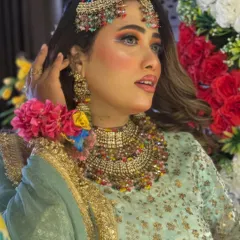 A close-up of the colorful Haldi makeup, paired with stunning multi-colored jewellery. The eye makeup uses shades of yellow, green, and orange.