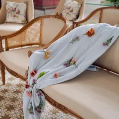The beauty of handmade details. For this engagement, we hand-stitched individual flowers onto this light blue throw, adding a delicate and personal touch to the classic rattan-weaved seating.
