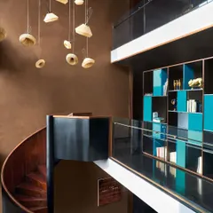 This spiral staircase, crafted in matte black metal and polished wood, is more than a connector; it's a sculptural punctuation mark in the architecture. Its form anchors the double-height space while allowing light to move freely.