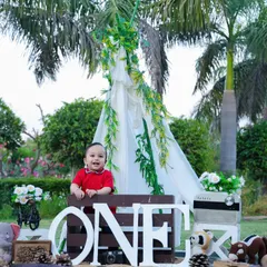 A wide shot of our outdoor setup for a first birthday, featuring a teepee, the number "ONE," and lots of fun props in a beautiful park.