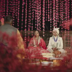 The couple during their wedding ceremony, framed by a curtain of delicate pink flowers. This shot highlights the beauty of layering textures and colors to create depth and romance.