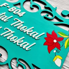 A close-up look at the hand-painted flowers on this teal wooden nameplate. These small details are what make each piece unique and personal.