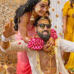 The pure, uninhibited joy of a Haldi ceremony. The couple, covered in turmeric and flower petals, share a playful and happy moment, perfectly capturing the spirit of the celebration.