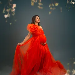 A fiery and passionate portrait. The vibrant red tulle gown and the mother's serene expression create a stunning contrast, framed by delicate blossoms for a touch of softness.