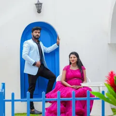 A high-fashion pose against a Santorini-inspired backdrop. The contrast of the bright pink gown against the white wall and blue door creates a striking and modern maternity photo.