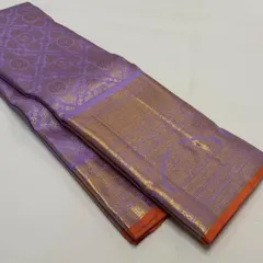 A folded view of a pure Kanchi Pattu silk saree in a lovely lavender shade with a gold and orange border. The quality of the silk and zari is evident.
