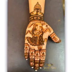 A single-hand Karwachauth design featuring a detailed couple portrait. The artwork is framed by a temple-style arch at the wrist, adding a traditional and spiritual element to the festive henna.