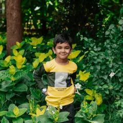 This young boy strikes a confident pose amidst the greenery. Outdoor sessions allow for beautiful, natural portraits with vibrant backgrounds.