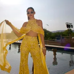 Alaya F radiates in a sunshine-hued embellished sharara. With a daring halter neckline and floor-sweeping sleeves, this look blends tradition with fearless fashion.