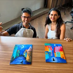 A couple proudly displaying their finished puzzle paintings. Each one tells a different story, with vibrant colors and whimsical scenes.