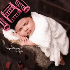 Getting pampered after a long nine months. This newborn is enjoying her spa day, complete with hair rollers and a cozy robe. We love creating these humorous and adorable setups.