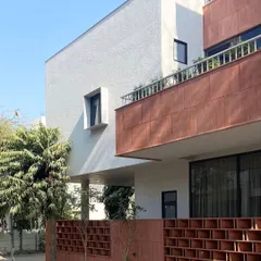 This view of the Jaipur House captures the layering of architectural elements. The projecting balcony and recessed windows create a play of light and shadow, adding depth and character to the building's exterior.