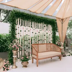 For an intimate and earthy engagement, I chose this elegant cane sofa. The backdrop is a screen of hanging tuberose garlands, framed by lush greenery, creating a look that is both minimalist and traditionally inspired.