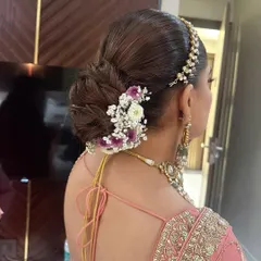 A closer look at a textured bridal bun for a D-day look. I've woven in fresh baby's breath and purple flowers to match the bride's pastel lehenga, creating a soft and romantic feel.