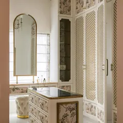 The bespoke walk-in closet at Verdant Manor, featuring floor-to-ceiling wardrobes with classic latticework and floral panel inlays. The central island provides storage and a surface for accessories.