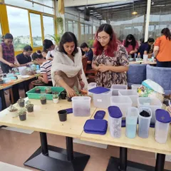 I'm here to guide you every step of the way. This photo shows me assisting a participant in selecting the right succulents for her open terrarium during a bustling weekend workshop.