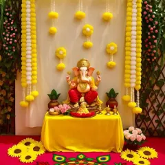 A beautiful Ganpati idol seated in a setting decorated with yellow and white artificial marigold garlands and a colourful rangoli mat. This is a classic and vibrant option for the festival.
