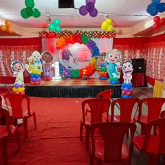 A fun Cocomelon-themed first birthday party setup. This includes a colorful balloon arch, character cutouts, and a large '1' marquee light to celebrate the big milestone.