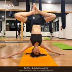 A student gracefully holds an inverted Baddha Konasana (Bound Angle Pose) in the aerial hammock. This variation helps open the hips and release tension in the lower back.