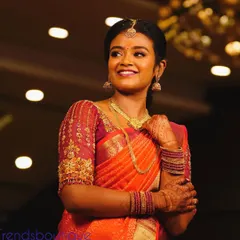 A happy client on her engagement day. She is wearing a beautiful orange silk saree with a custom-designed blouse featuring organza puff sleeves and delicate embroidery.