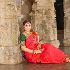 A serene portrait of a bride seated on the temple floor, surrounded by massive stone pillars. The scale of the architecture adds a sense of grandeur to the image.