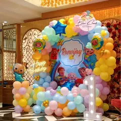 A full view of the Cocomelon themed party we organized. This setup features a custom character backdrop, a multi-colored balloon arch, and a light-up number '1' to celebrate a first birthday.