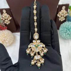 A close-up of the 'Noor Nazaakat' maang tikka, featuring moissanite, kundan, and delicate pearl drops.