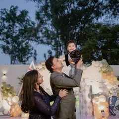 A beautiful family portrait at a golf-themed first birthday party, with the father lifting his son up in happiness.