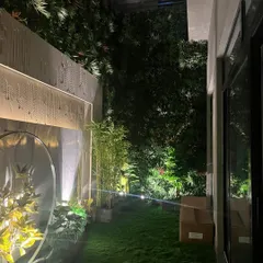 A night view of a garden where my artificial turf provides the perfect green base. The lighting highlights the texture of the grass and the surrounding artificial bamboo and green walls.