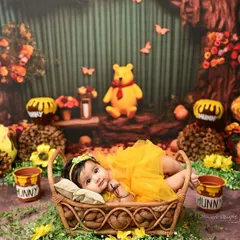 A sweet newborn girl in a Winnie the Pooh inspired setting. Lying peacefully in a basket, this portrait captures the serene beauty of the first few weeks of life.