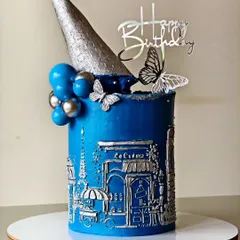 I brought a touch of Paris to this birthday with a detailed bas-relief cityscape, sculpted entirely from buttercream. The silver finish on the classic blue cake, topped with a modern cone and delicate butterflies, creates a truly unique and elegant centerpiece.