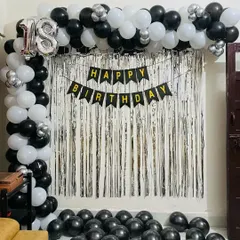 A classic and bold backdrop for an 18th birthday. This setup includes a silver shimmer curtain, a 'Happy Birthday' banner, and a balloon frame in a striking black and white color scheme with silver accents.