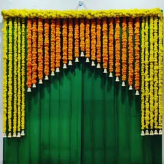 A classic door decoration to brighten up your home for any festival. This design uses strings of yellow and orange marigolds to create a beautiful arch over the door, with hanging white bells for an auspicious touch.