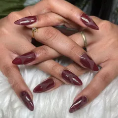 A stunning stiletto set in a deep burgundy jelly polish, creating a semi-sheer, high-gloss finish.