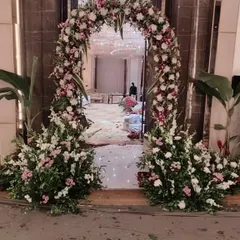A classic floral archway I created for the entrance to a wedding hall. The arch is made with a mix of white, pink, and green fresh flowers and foliage.