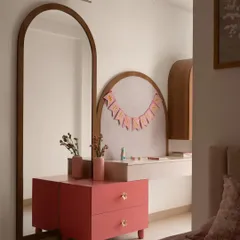 A custom vanity and dresser area designed for a young girl's room. The soft pink drawers and arched details create a delightful personal space, complemented by a full-length arched mirror.