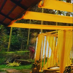A classic Haldi ceremony setup featuring a bright yellow draped mandap, hanging marigolds, and traditional brass urlis for the ritual.