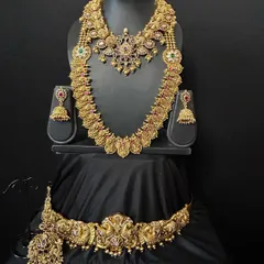 This stunning temple jewellery set combines a short necklace, a long coin haaram, and an intricate vaddanam. The craftsmanship is evident in the detailed deity motifs, making it a truly divine choice for your wedding day.